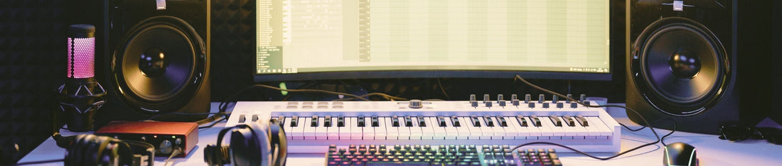 müzik projesi bilgisyar ekranı, hoparlörler ve masada midi klavye ile klavye