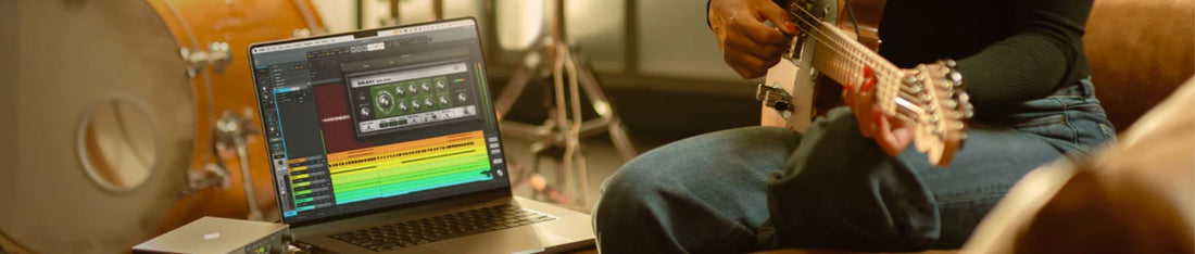 gitar çalarken universal audio LUNA daw kullanan bir müzisyen, gitar ve bilgisayar